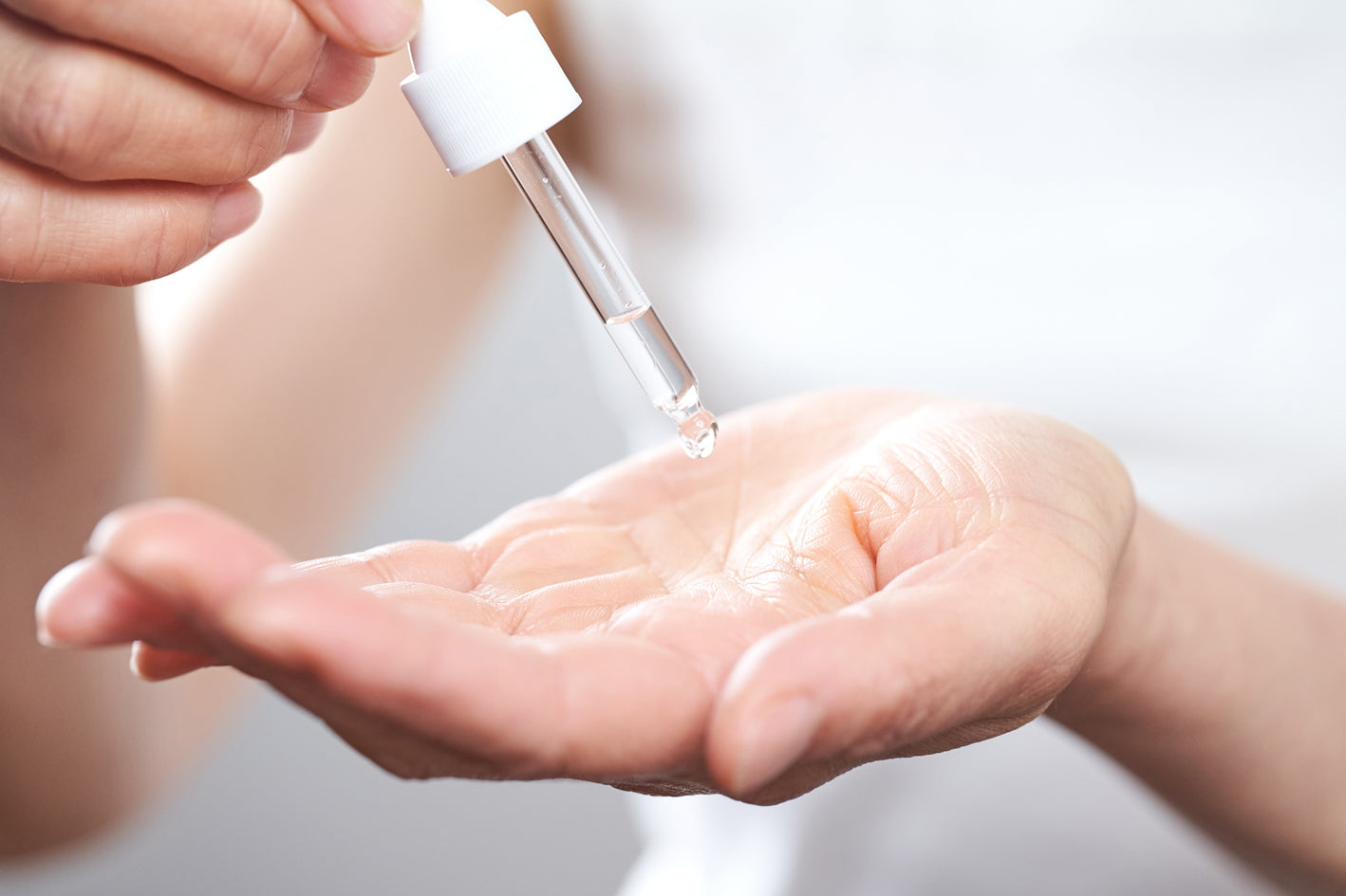 A drop of SNOVA serum falling from the dropper into a palm.